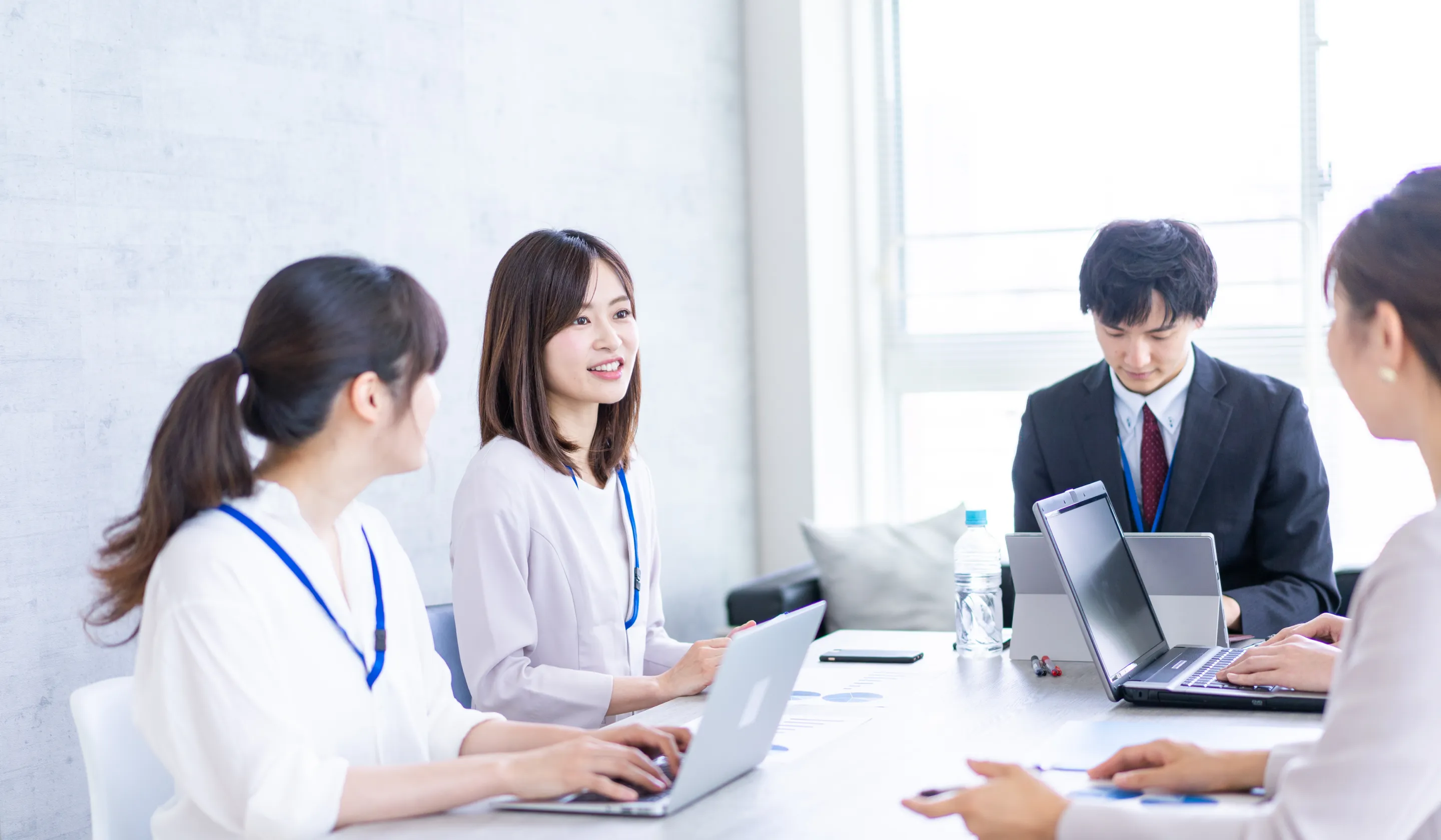 テーブルを囲んでノートパソコンを使っている人々のグループ