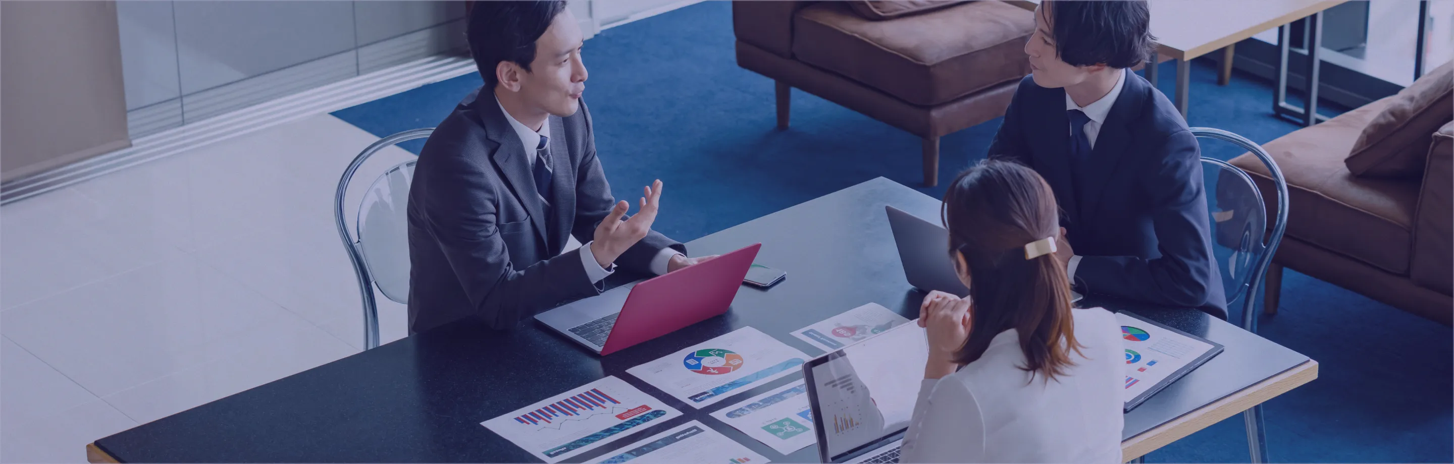  三人がテーブルに座り、各自のノートパソコンを使っている様子