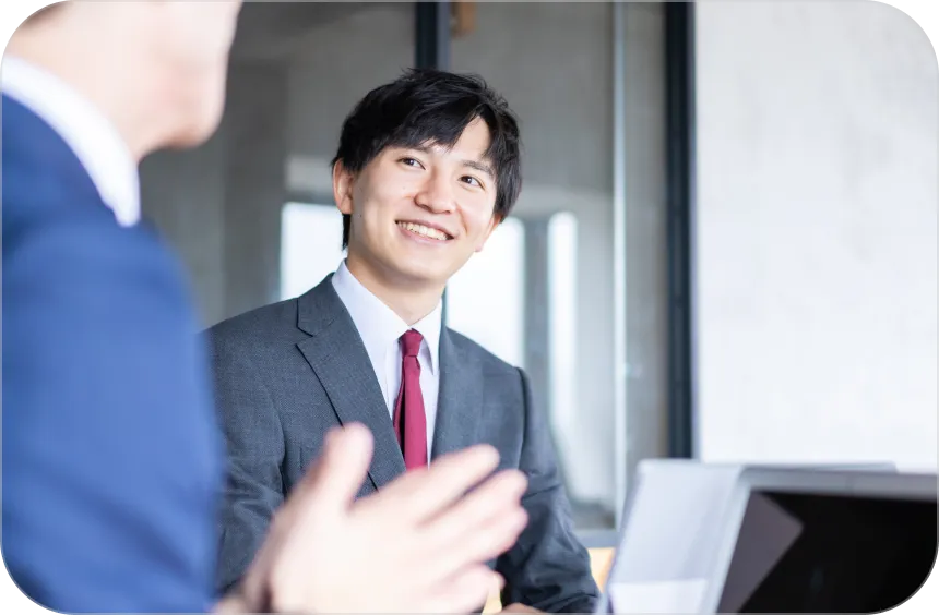  スーツを着た二人の男性がテーブルに座り、ノートパソコンを使っている様子