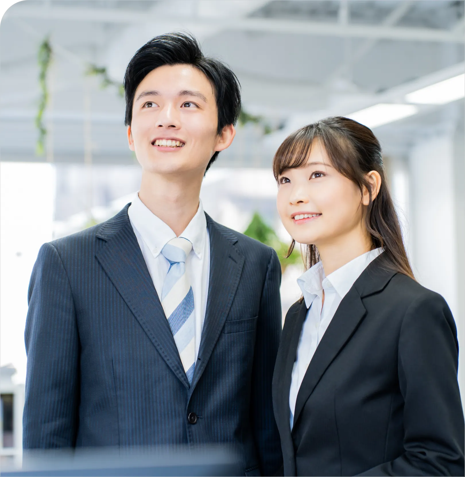 スーツ姿の男女が隣り合って立っている様子